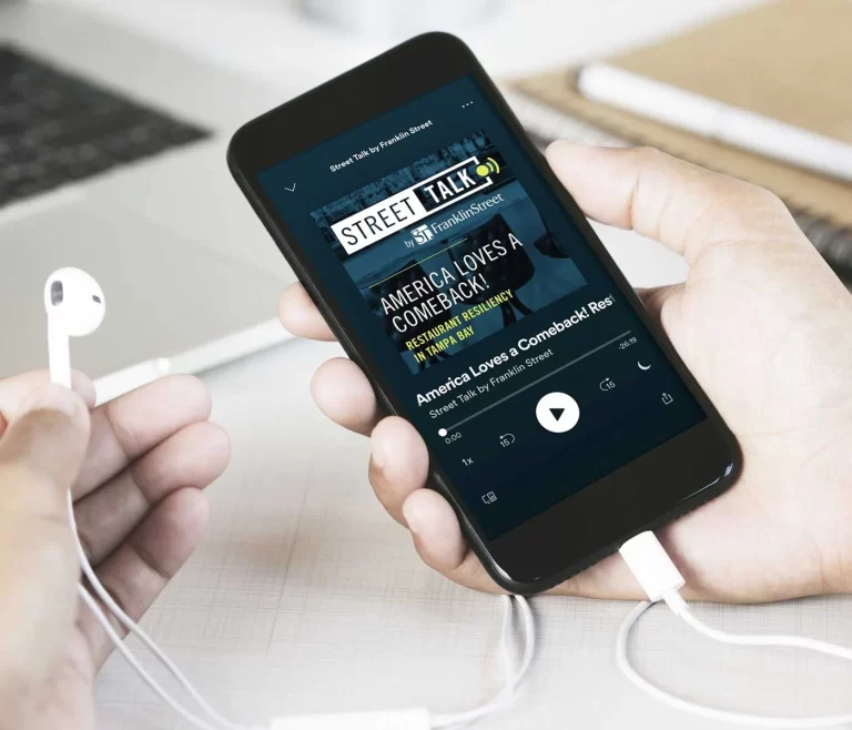 A user holding a cellphone displaying Franklin Street's podcast art.